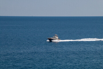 Fototapeta premium Estela dejada en la superficie del mar por un yate. Mar Jónico azul profundo, frente a la costa de Santa Maria di Leuca, Italia, en un día soleado de verano.