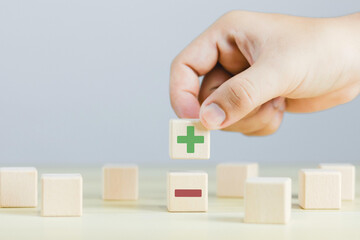Wooden blocks showing plus and minus signs. The concept of antithesis. Decision making. Positive or negative business choice. Analysis of advantages and disadvantages Comparison	

