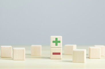 Wooden blocks showing plus and minus signs. The concept of antithesis. Decision making. Positive or...