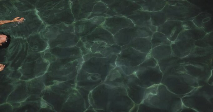 Fashionable tanned girl model in black bikini relaxing in swimming pool spa. High quality slow-motion cinematic 4k footage