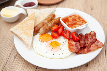 Full English breakfast set with sausage, egg, bacon, baked bean, ham, tomato and toast