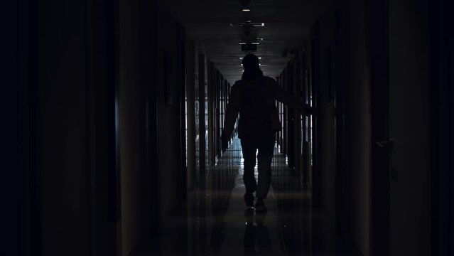 Silhouette of man in dark corridor walk away.