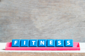 Tile alphabet letter with word fitness in red color rack on wood background