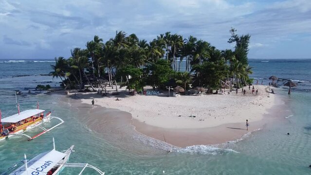 Aerial, Guyam island in Siargao tour Boats and People on small uninhabited tropical islet with white sand beach, palm trees and turquoise water lagoon. Travel concept