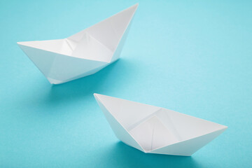 White paper ships on blue background indicate direction, unity, competition, goals, team group concept.