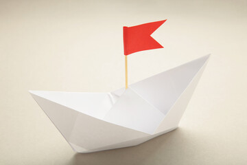 White paper ships and red flags on grey background.