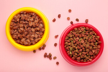 Wet and dry pet food in feeding bowls on pink background.
