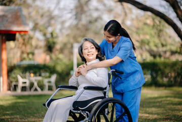 Elderly asian senior woman on wheelchair with Asian careful caregiver.