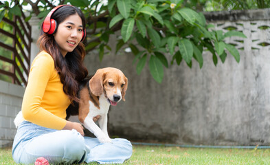 Young asian woman and beagle puppy relaxing on weekends in the front yard.