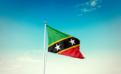 Waving Flag of Saint Kitts and Nevis in Blue Sky. The symbol of the state on wavy cotton fabric.
