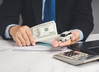 Car loan or Auto title loan. US dollar bills in a hand businessman while sitting at the table