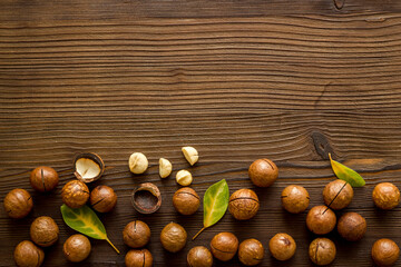 Shelled macadamia nuts with green leaves. Healthy snack background