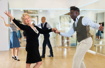 Lady learning to dance lindy hop with man in dance school