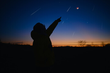 Silhouette of a man with Milky Way starry skies, lunar eclipse and meteor shower.