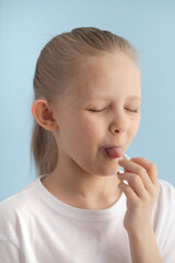 The child puts a pill in his mouth. The girl is taking medicine.