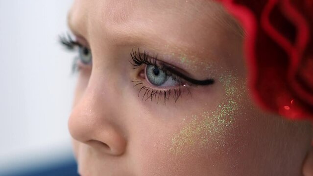 Macro eye with makeup. Bright theatrical makeup for the stage. The child is staring at the stage. Long eyelashes. Festive, carnival make-up