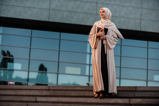 Full length portrait of a successful Muslim business woman in hijab near the office building.