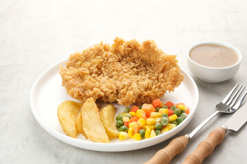 Crispy Chicken Steak with french fries and vegetables. 
