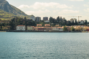 Fototapeta premium Lake Como from the shore of the city of Lecco. View of the Alps mountains, buildings and the town of Malgrate. 