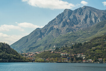 Fototapeta na wymiar Lake Como from the shore of the city of Lecco. View of the Alps mountains, buildings and the town of Malgrate. 