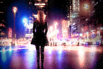 View through glass window with rain drops on blurred reflection silhouettesof a girl in walking on...