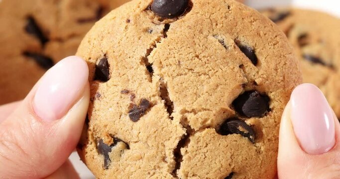 Hands break a chocolate chip cookie slow. Close up first person view. The sweet treat is divided in half. American chocolate chip cookie. High quality 4k footage.