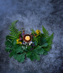 wiccan altar with candle, flowers, oak and fern leaves on dark abstract background. Witchcraft...