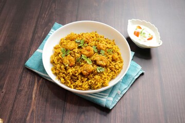 Prawns Biryani or shrimp Pulao. also called jheenga pilaf or jhinga biryani in India. known as Kolambi bhat in Marathi. Garnished with mint leaves, and coriander along with yogurt Raita. Copy space