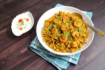 Prawns Biryani or shrimp Pulao. also called jheenga pilaf or jhinga biryani in India. known as Kolambi bhat in Marathi. Garnished with mint leaves, and coriander along with yogurt Raita. Copy space