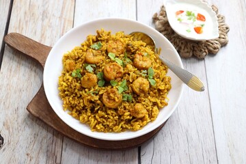 Prawns Biryani or shrimp Pulao. also called jheenga pilaf or jhinga biryani in India. known as Kolambi bhat in Marathi. Garnished with mint leaves, and coriander along with yogurt Raita. Copy space
