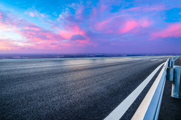Asphalt highway road and red sky clouds at sunset