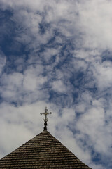 Fototapeta na wymiar old wooden church against the blue sky in Ukraine, wooden roof with a cross
