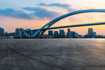 Stoff pro Meter Asphalt road and bridge with city skyline at sunset © ABCDstock
