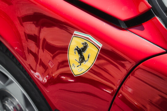 Side view of a red Ferrari brand luxury sports car with the black horse logo sticker on the body, no people