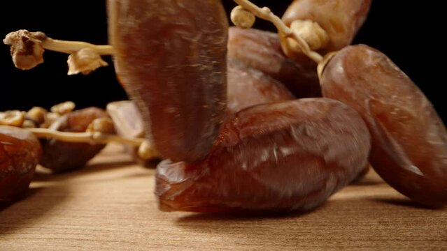 With a black background, I gently pick up a dried date on a branch from the table, creating a close-up macro slide shot.