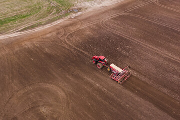 Obraz premium A tractor with a mounted disc harrow plow a field for sowing crops. Agriculture concept. Sowing grain crops