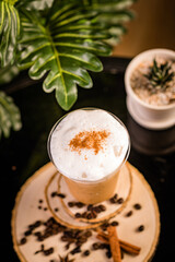 Obraz na płótnie Canvas iced cappuccino coffee In a glass ready to serve Beautifully decorated with green leaves and coffee beans on a black background.