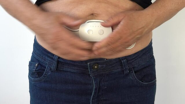 A woman activates a electrostimulation device on her belly for weight loss
