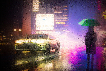 view through glass window with rain drops on blurred reflection silhouette of a girl on a city street after rain and colorful neon bokeh city lights, night street scene. Focus on raindrops on glass	