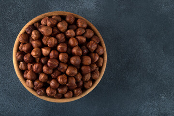 View of a bowl full of hazelnuts on a black background
