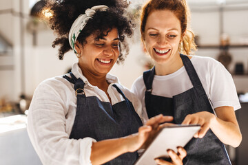 Two restaurant workers using a touchscreen tablet together