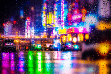 Fototapeta na wymiar View through a glass window with raindrops on city streets with cars in the rain, bokeh of colorful city lights, night street scene. Focus on raindrops on glass