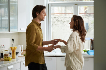 Happy couple dancing in kitchen when cooking dinner together