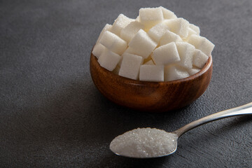 Cube sugar and granulated sugar on black background
