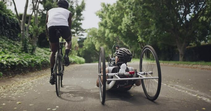 Sports, cycling and adaptive bicycle for men in park for fitness, physical therapy and person with disability rear view. Exercise, friends and man athlete in a wheelchair bike for workout or wellness