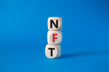 NFT - non-fungible token symbol. Concept word NFT on wooden cubes. Beautiful blue background. Business and NFT concept. Copy space.
