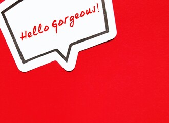 Speech sticker on red copy space background with handwriting 'Hello Gorgeous' , concept of daily...