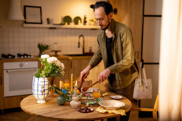 Man serves pasta meal into plates on dining table at cozy home interior