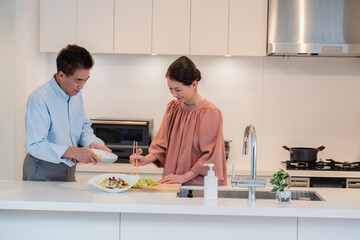 キッチンで一緒にクッキングを楽しむシニアの夫婦
