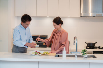 キッチンで一緒にクッキングを楽しむシニアの夫婦